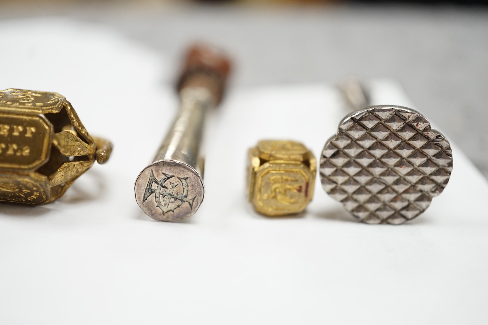 A group of twenty-five steel, gilt metal or nickel fob or desk seals, mostly 19th-century, including a steel swivel seal, a seal with boxwood finial modelled as a hand holding a ball and a nickel multi seal